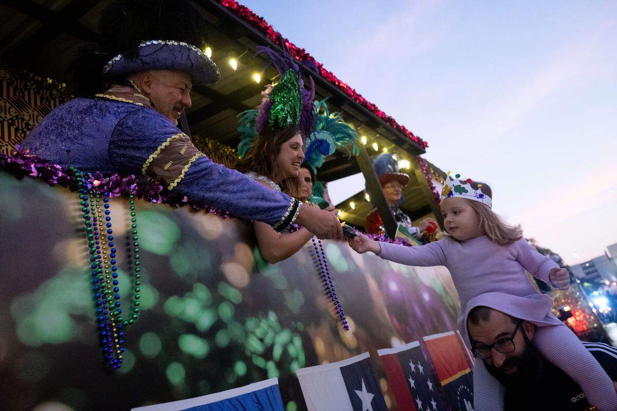 Candy is handed out to a child riding on her father’s shoulders during a 12th Night Celebration in Biloxi on Monday, Jan. 5, 2026.