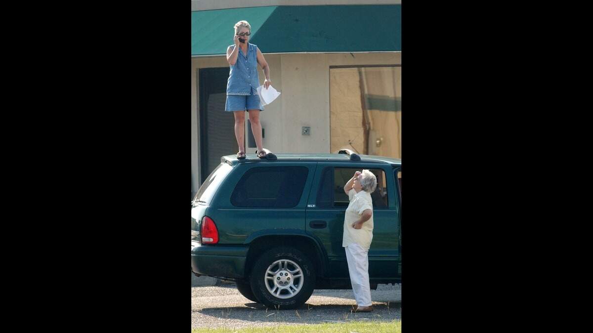 Nancy Madden of Gulfport stands on top of her car on Friday Sept. 2, 2005, to get a better cell phone signal as she and her mother, Nora Clay, try to reach family members and insurance companies following Hurricane Katrina. A new map shows that 90 percent of Mississippi has adequate cell phone service, but residents said there are lots of ‘dead zones’ out there.