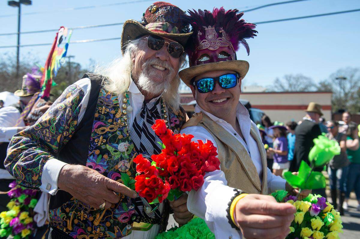 Members of the Ole Biloxi Marching Club hand out flowers during the Jackson County Carnival Association Mardi Gras parade in Pascagoula on Saturday, March 1, 2025.
