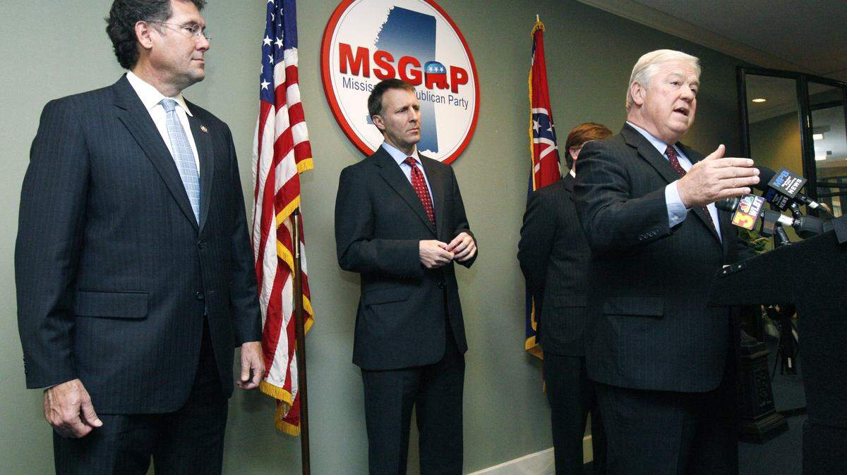 Longtime state Sen. Gray Tollison of Oxford, center, listens to Gov. Haley Barbour explain why Tollison switched from Democrat to Republican at a news conference at state GOP headquarters in Jackson, Miss., as U.S. Rep. Gregg Harper, R-Miss., listens Thursday, Nov. 10, 2011. The GOP already held the majority in the 52-member Senate.