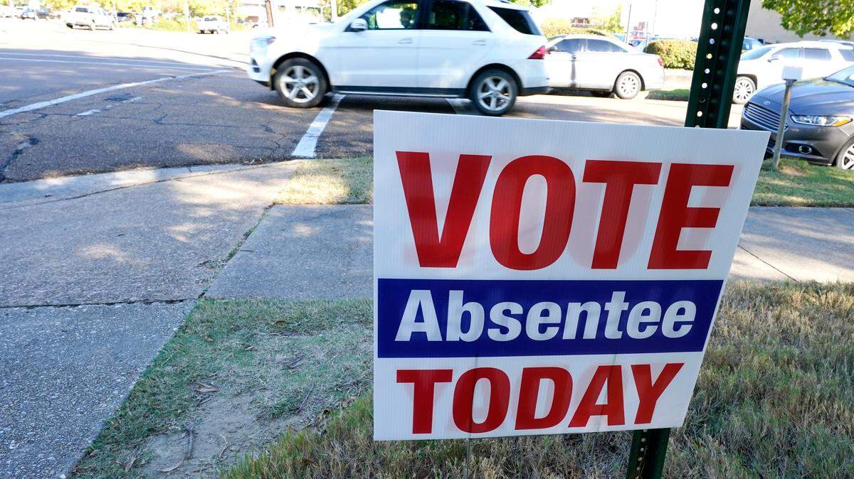 A sign encouraging voters to vote absentee in light of COVID-19 precautions rests on the grounds of the Hinds County Courthouse in Jackson in 2020. A federal judge issued an order Tuesday to block a new Mississippi law that would restrict who could help people with absentee voting.(AP Photo/Rogelio V. Solis)