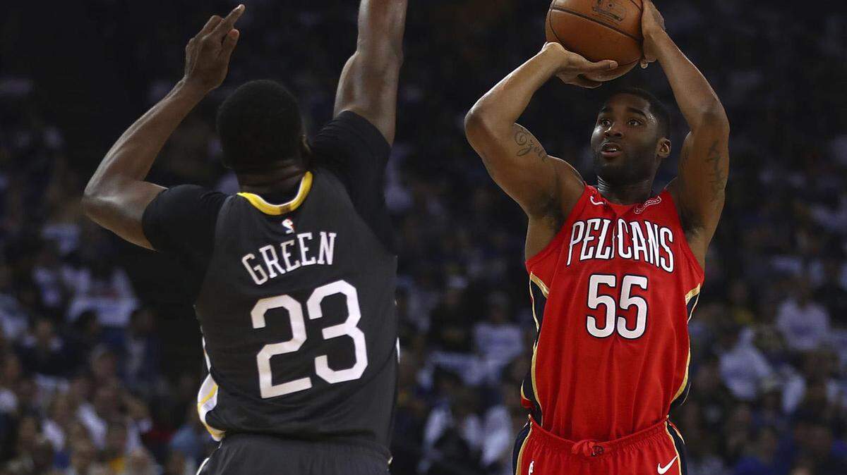New Orleans Pelicans' E'Twaun Moore, right, shoots against Golden State Warriors' Draymond Green during the first half of an NBA basketball game in Oakland, Calif., on April 7, 2018. 