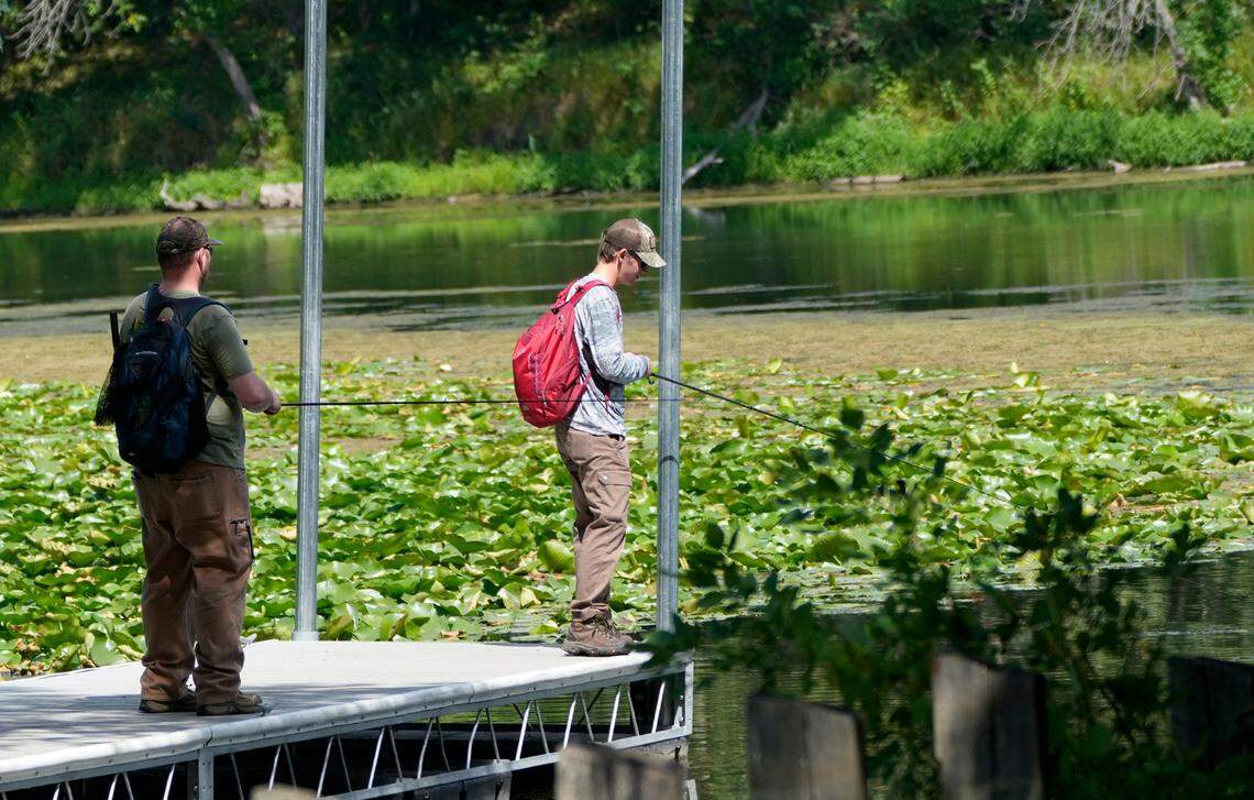 Josh White (left) and his son Ethan try their luck fishing off a pier on Third Lake in western Trempealeau, Wisconsin on Aug. 25, 2023.