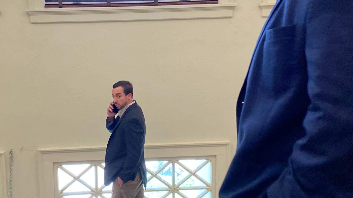 Alan Moran speaks on a phone Wednesday in front of his father, former state Sen. Philip Moran.