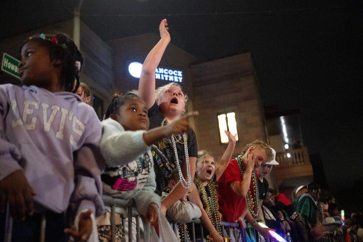 Children cheer for throws from parade floats during the Krewe of Neptune parade in Biloxi on Saturday, Feb. 14, 2026.