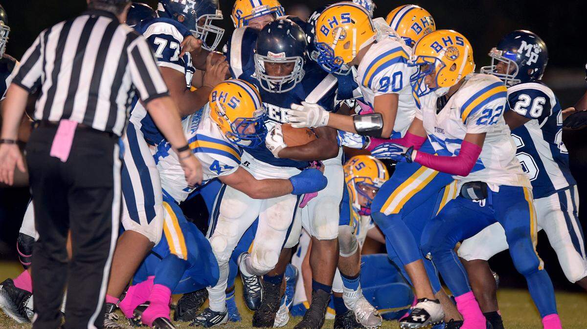 GLENN ANDREWS/SPECIAL TO THE SUN HERALDBay High defenders wrap up Moss Point running back Travis Marion.