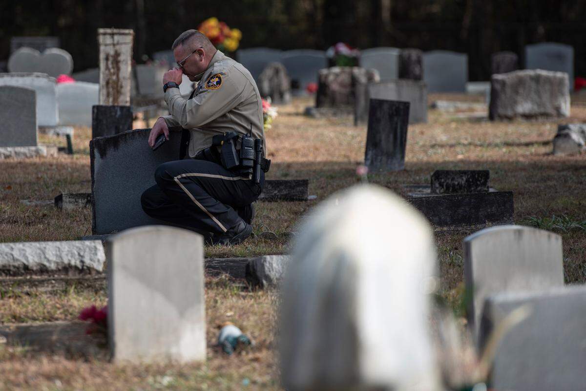 A law enforcement officer reacts as a final radio call is played during a graveside service for George County Sheriff’s Deputy Jeremy Malone at Tanners Cemetery in George County on Friday, Jan. 12, 2024.
