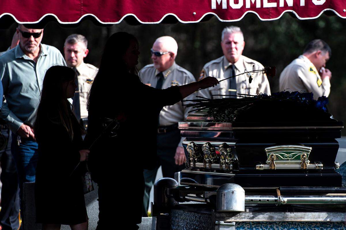 Family place roses on George County Sheriff’s Deputy Jeremy Malone’s casket during a graveside service for Malone at Tanners Cemetery in George County on Friday, Jan. 12, 2024.