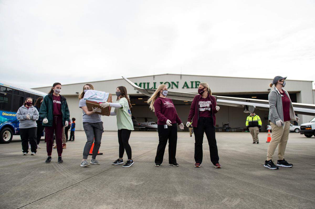 Veterinary medicine students from Mississippi State form a chain to help carry the turtles from the airplane to a bus waiting to transport the turtles to the Institute for Marine Mammal Studies at the Gulfport Airport in Gulfport on Monday, Dec. 20, 2021.