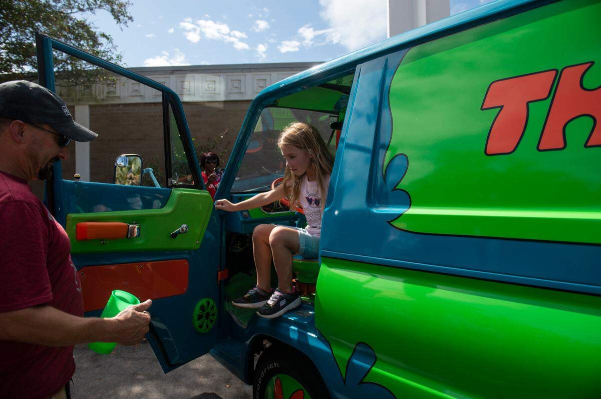 Dave Cardillo helps his daughter Samantha Cardillo, 7, out of a Mystery Machine look alike during View the Cruise in downtown Gulfport on Sunday, Oct. 3, 2021. Cardillo said he and his daughter have seen all the Scooby Doo movies and shows.