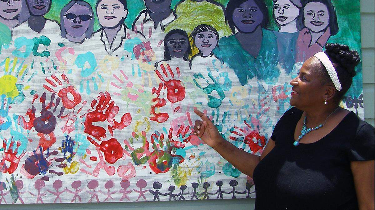 Sharon Hanshaw stands next to a mural featuring volunteers and workers at Coastal Change for Women, an Oxfam American partner organization, in East Biloxi on June 20, 2014. 