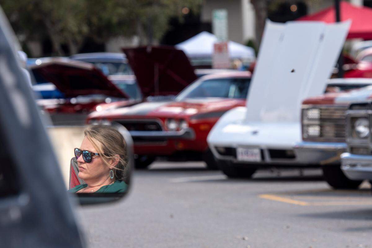 A woman is reflected in the mirror of a classic car during View the Cruise, one of the first events of Cruisin’ The Coast, in Gulfport on Sunday, Oct. 6, 2024.