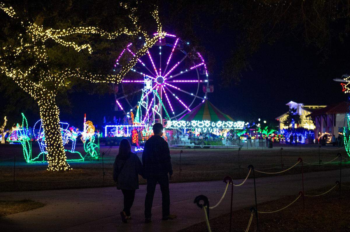 A couple strolls through Jones Park during the Harbor Lights Winter Festival in Gulfport on Thursday, Dec. 2, 2021.
