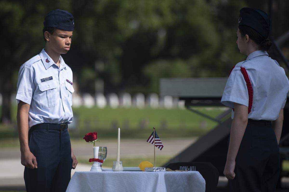 Civil Air Patrol members stand beside a table representing prisoners of war and those killed in action during a Memorial Day ceremony at Biloxi National Cemetery in Biloxi on Monday, May 26, 2025.