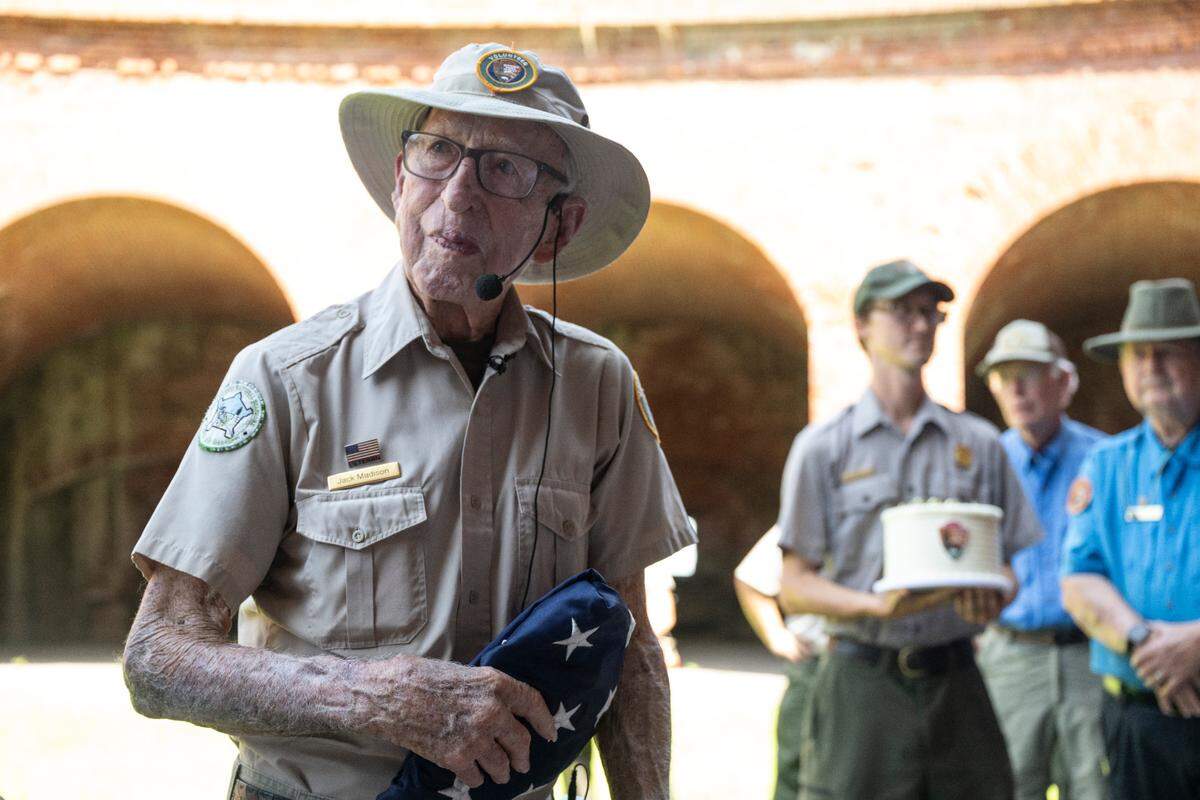 Jack Madison, a volunteer tour guide for Gulf Islands National Seashore, is presented with a flag and a birthday cake after his final tour of Fort Massachusetts on Ship Island on Friday, July 11, 2025 — his 100th birthday.