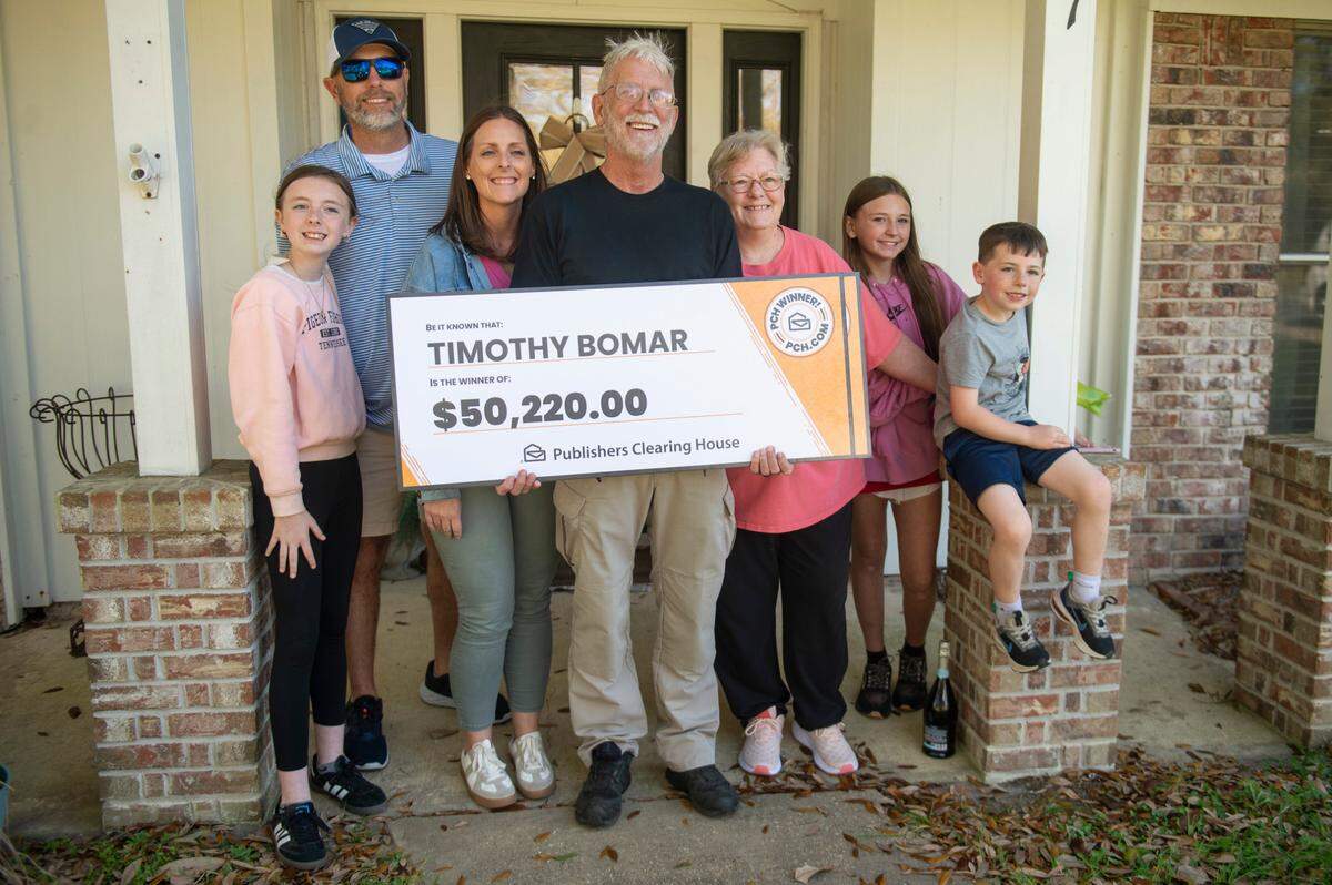 The Bomars and their kids and grandkids pose for a photo with the $50k check outside their home in Ocean Springs on Wednesday, March 19, 2025.
