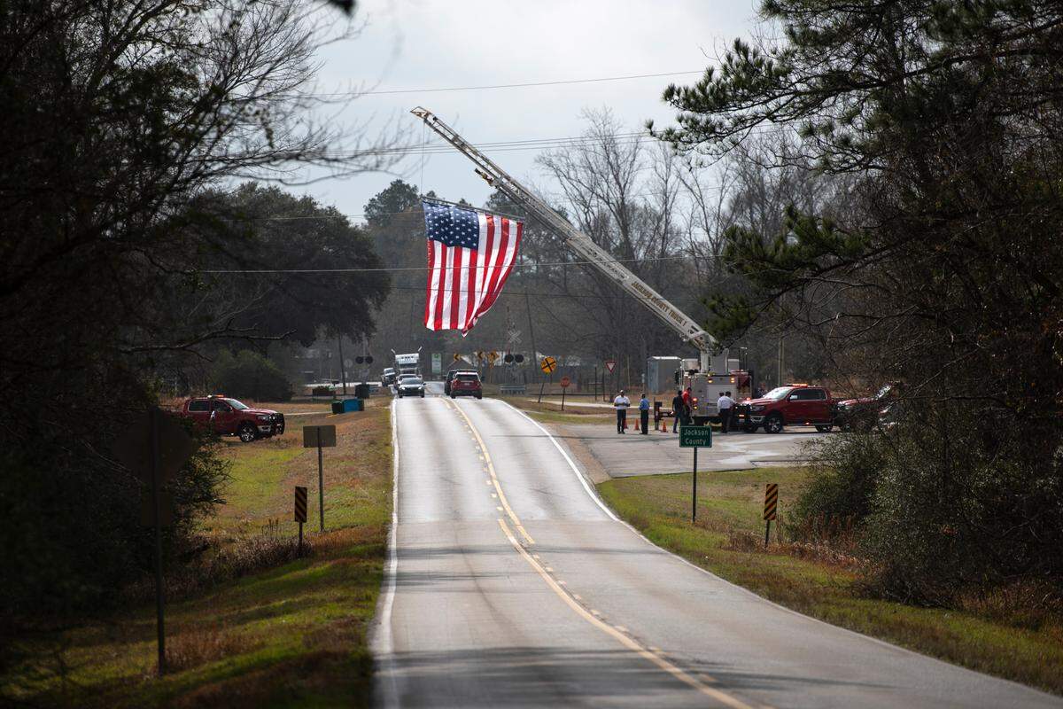 An American flag is waved above Highway 613 at the county line in honor of George County Sheriff’s Deputy Jeremy Malone in George County on Friday, Jan. 12, 2024.