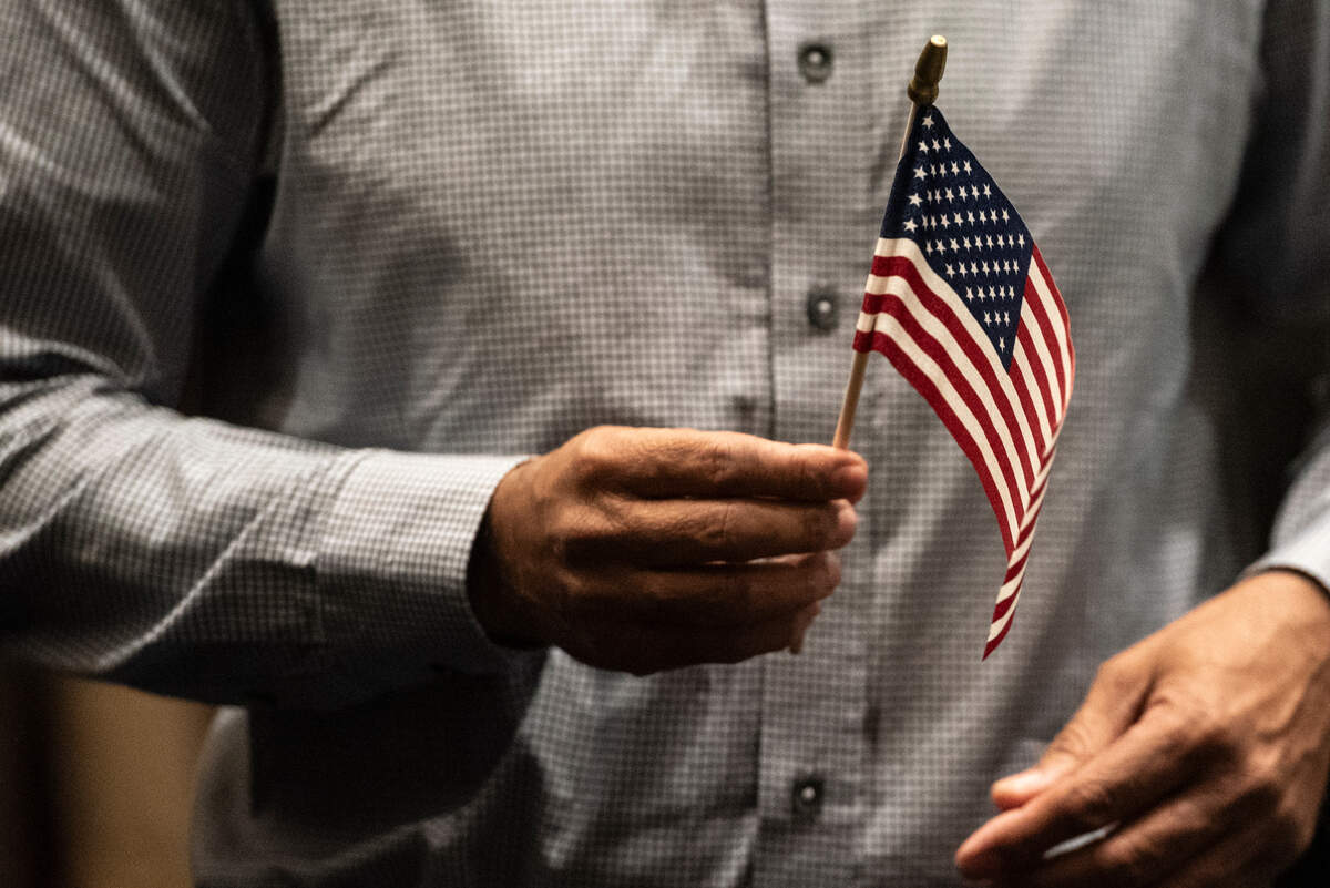 A newly naturalized American citizen holds an American flag during a naturalization ceremony at Dan M. Russell Courthouse in Gulfport on Thursday, Oct. 19, 2023.
