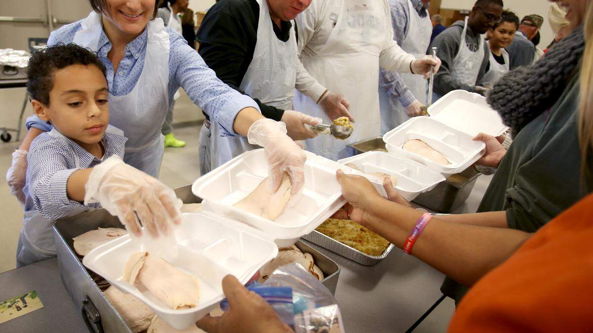 AMANDA McCOY/SUN HERALDNarissa Behrens and her son, R.J. Lowell, Jr., 7, serve turkey as hundreds of volunteers help to assemble Thanksgiving meals for those in need on Thursday, November 26, 2015, at the Lyman Community Center in Gulfport. The Gulf Coast Public Safety's Feed the Needy program delivers meals to 1800 people throughout Harrison County.