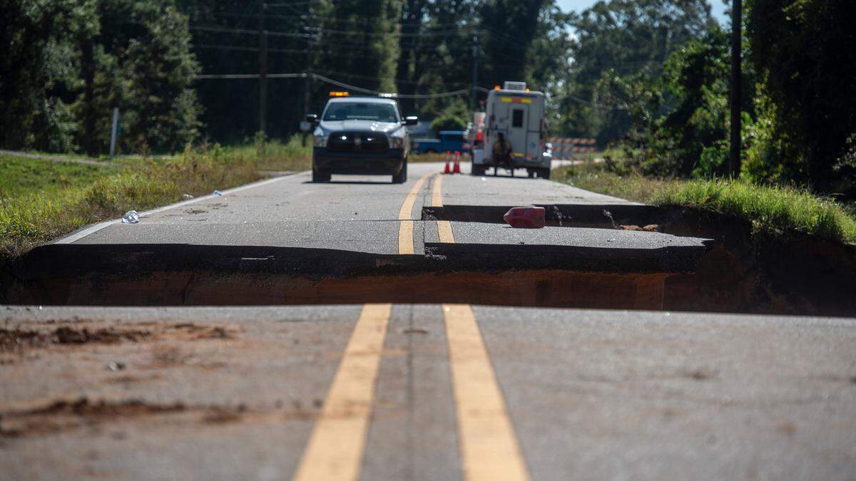 Trucks sit on Highway 26 near where part of the road collapsed Monday night, killing two and injuring 10 on Tuesday, Aug. 31, 2021