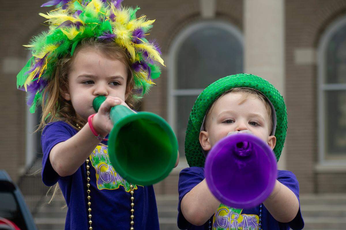 Gauge Morrisette, 3, right, and Anna Jane Morrisette, 7, play with plastic horns during the Krewe of Gemini parade in downtown Gulfport on Saturday, Feb. 10, 2024.