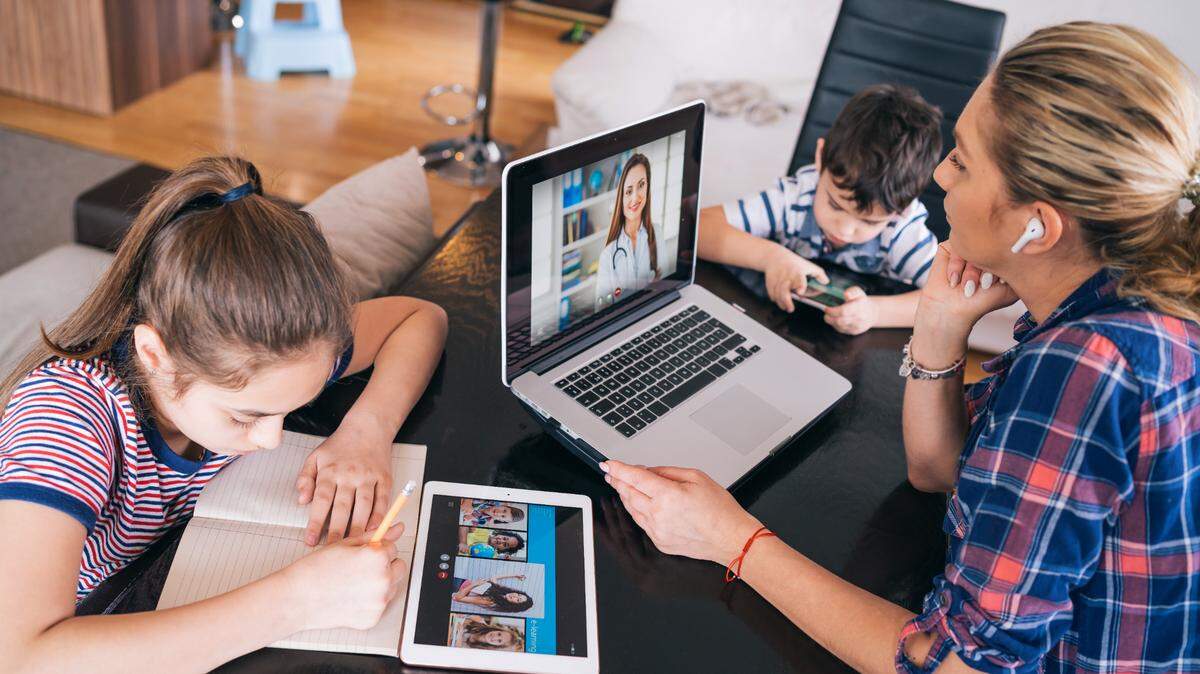 This mother is talk with doctor while watching two kids staying home. Telehealth services are on the rise since the start of the pandemic.