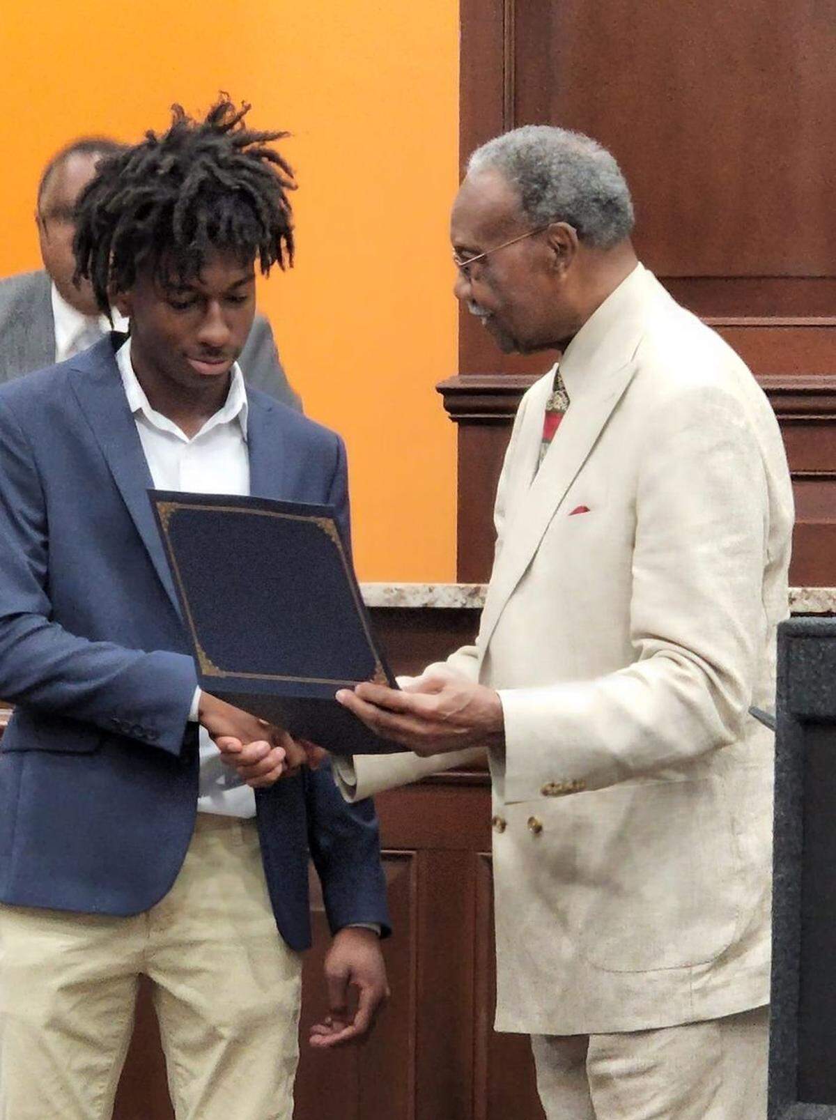 Moss Point Mayor Billy Knight presents Corion Evans, who rescued a Moss Point police officer and three others from drowning, with a Certificate of Commendation at a Board of Aldermen meeting in Moss Point on July 5, 2022.