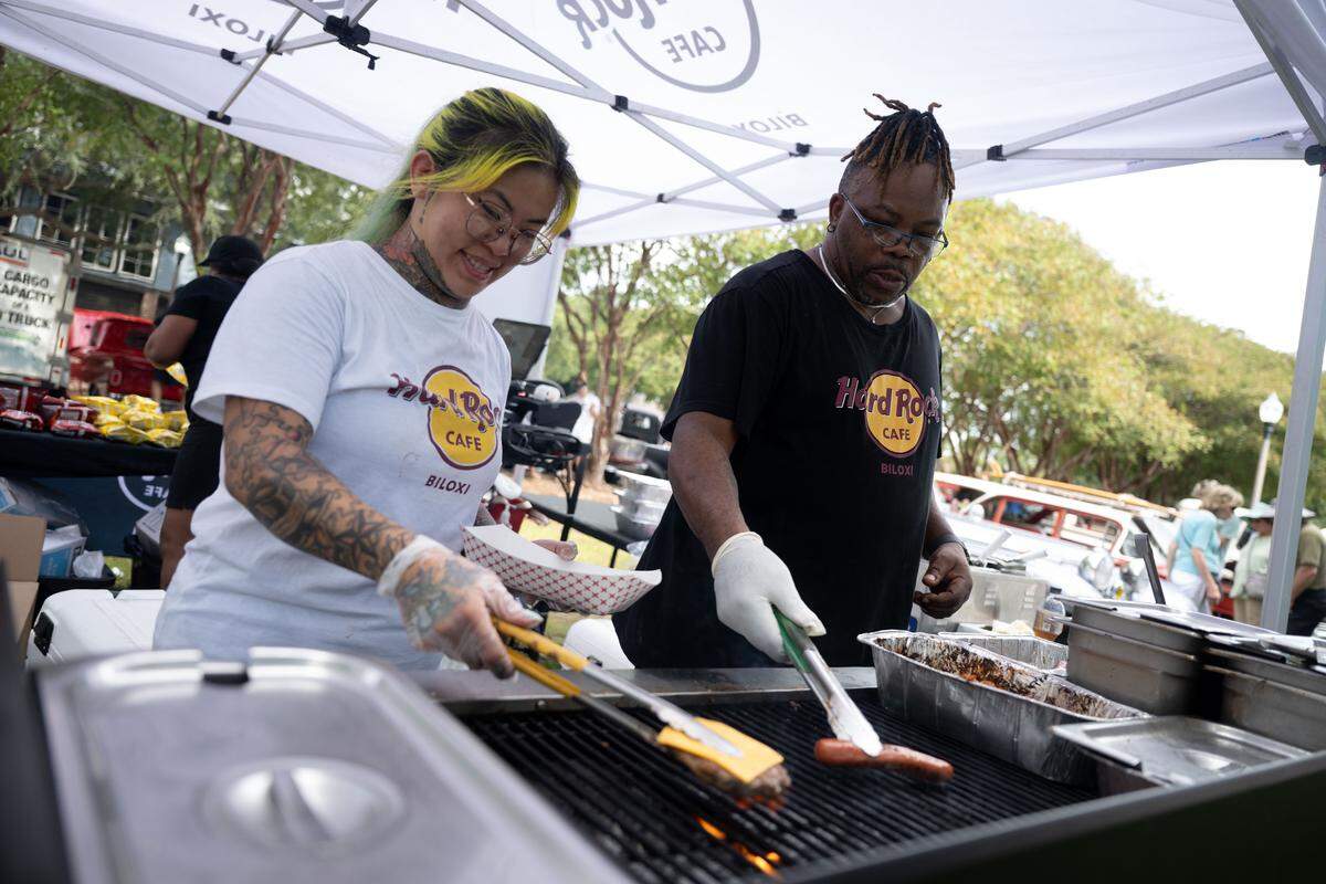 Sidney Lacy, right, cooks hot dogs at a Hard Rock food stand during the Biloxi Block Party.