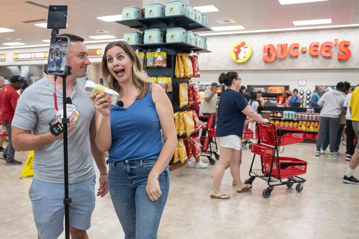 New Orleans food influencers Carla Pesono and Brian Maurice film social media content during the opening of Buc-ee’s first Mississippi location in Harrison County on Monday, June 9, 2025.
