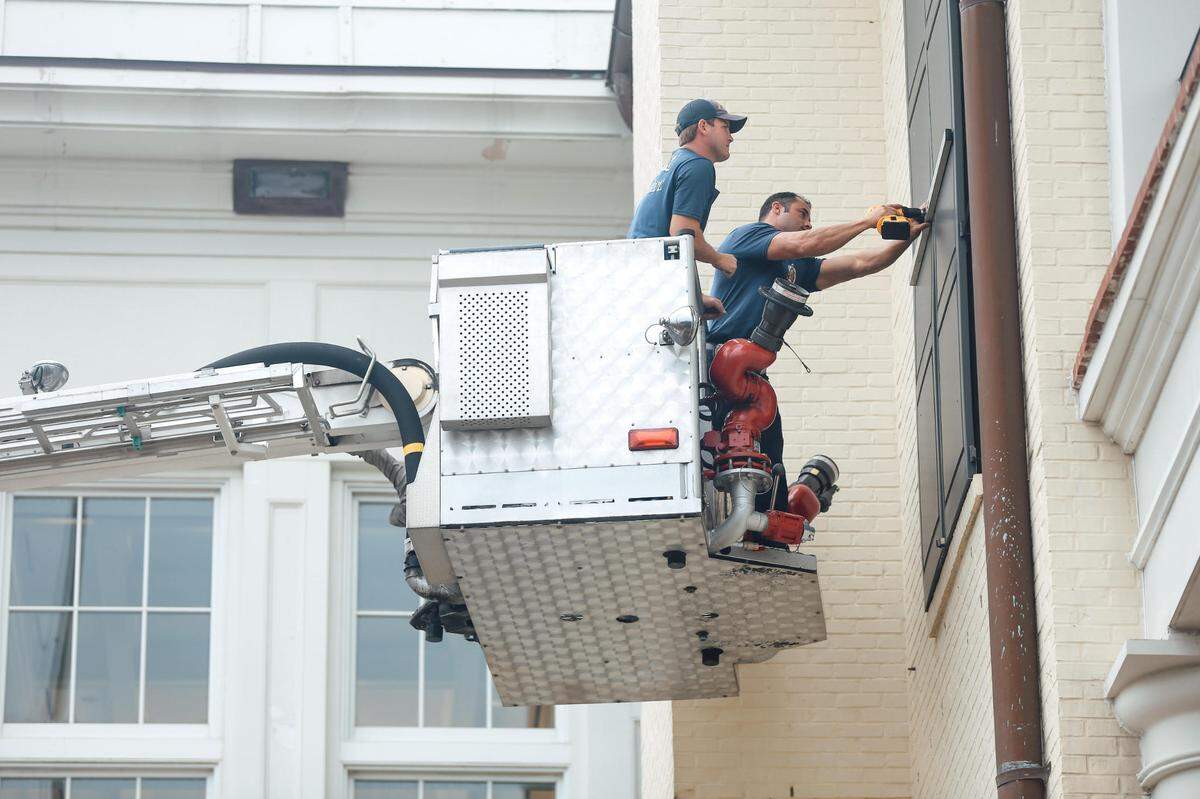 Two Biloxi firemen shutter a second story window of the Biloxi Visitors Center on U.S. 90 Wednesday morning. The Mississippi Coast city is preparing ahead of Zeta.