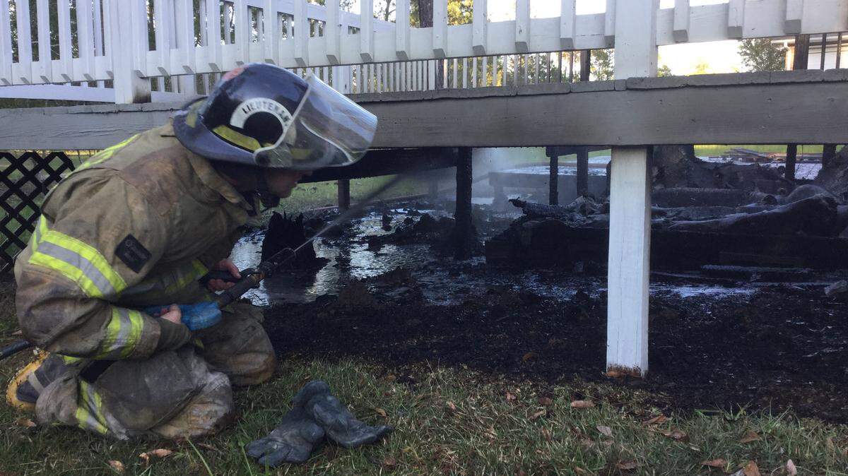 PAT SULLIVAN/HARRISON COUNTY FIRE SERVICES 
 A Harrison County firefighter helps contain a structure fire that damaged a deck in the rear of a home in central Harrison County on Monday.