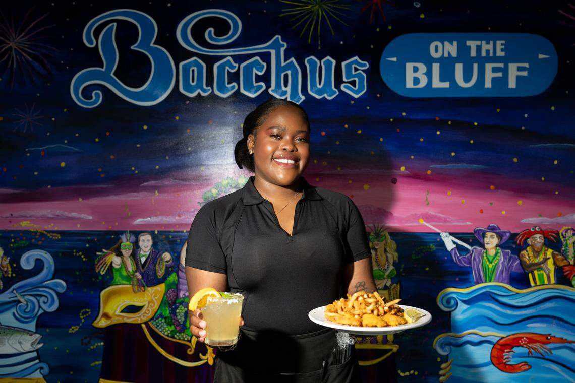 Abby Gipson brings a Nectar of the Gods cocktail and a Gulf shrimp platter to the table at Bacchus on the Bluff in Gulfport on Wednesday, March 11, 2026.