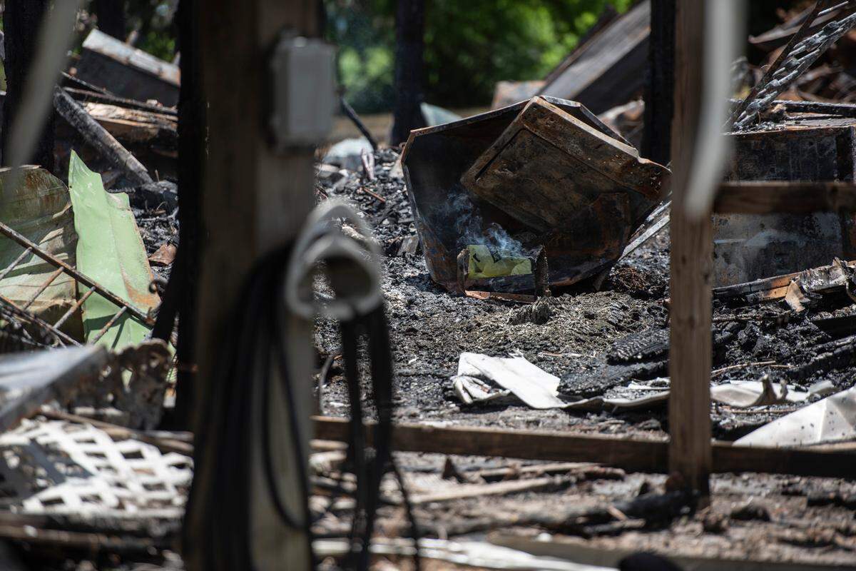 A piece of wood still smolders on Tuesday, May 31, 2022 after a fire tore through two houses on Highway 603 in Kiln on Saturday night, killing two.