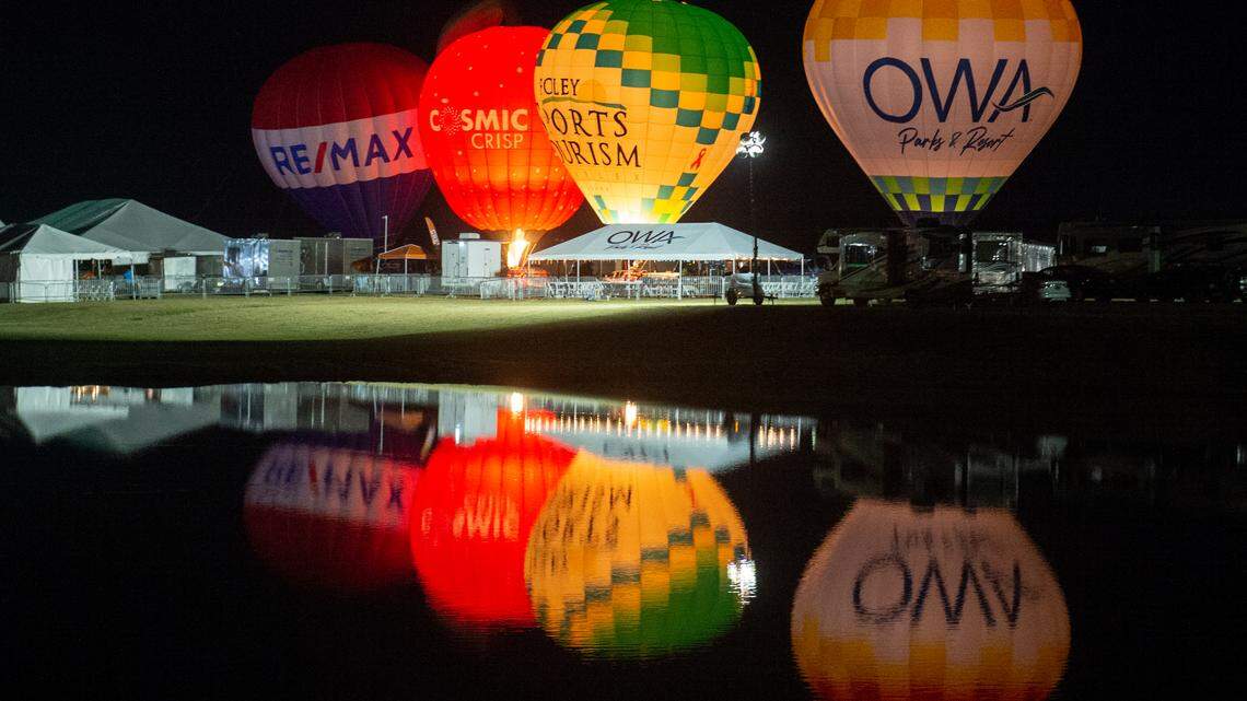 Several hot air balloons are reflected in a lake during the Gulf Coast Hot Air Balloon Festival at OWA in Foley, Alabama on Thursday, May 4, 2023.