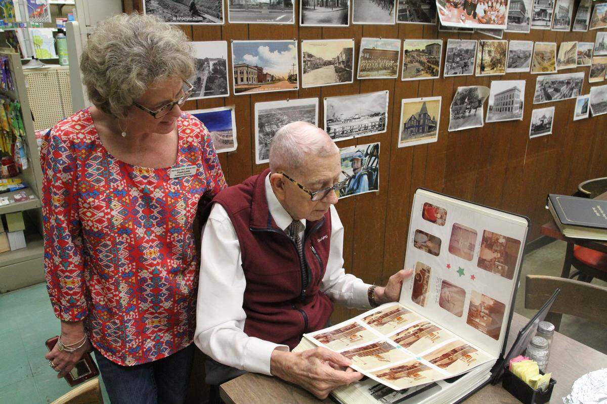 Poem Love looks over a Triplett-Day scrapbook with her father, Jim Day, at Triplett-Day Drugs, where she has worked since she graduated high school. Love and her father will be moving from full-time work at the downtown location, which closes at month’s end, to part-time jobs at the family pharmacy in Orange Grove.