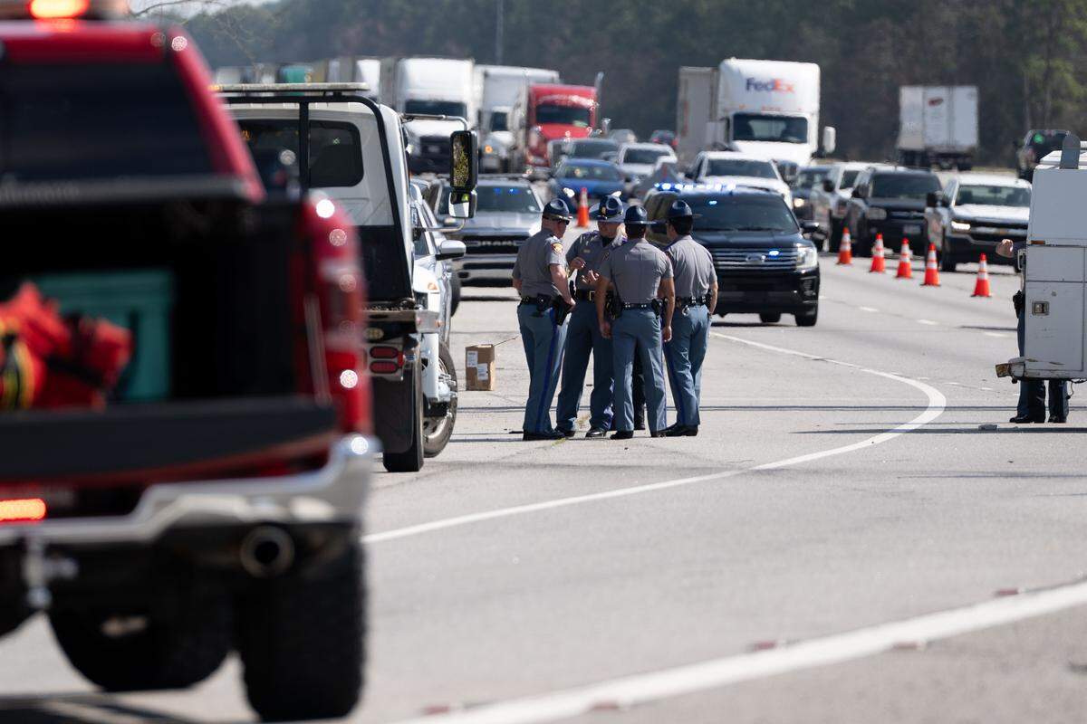 Police officers huddle at Exit 50 on I-10 as traffic begins to build up behind them on Wednesday, Feb. 18, 2026.