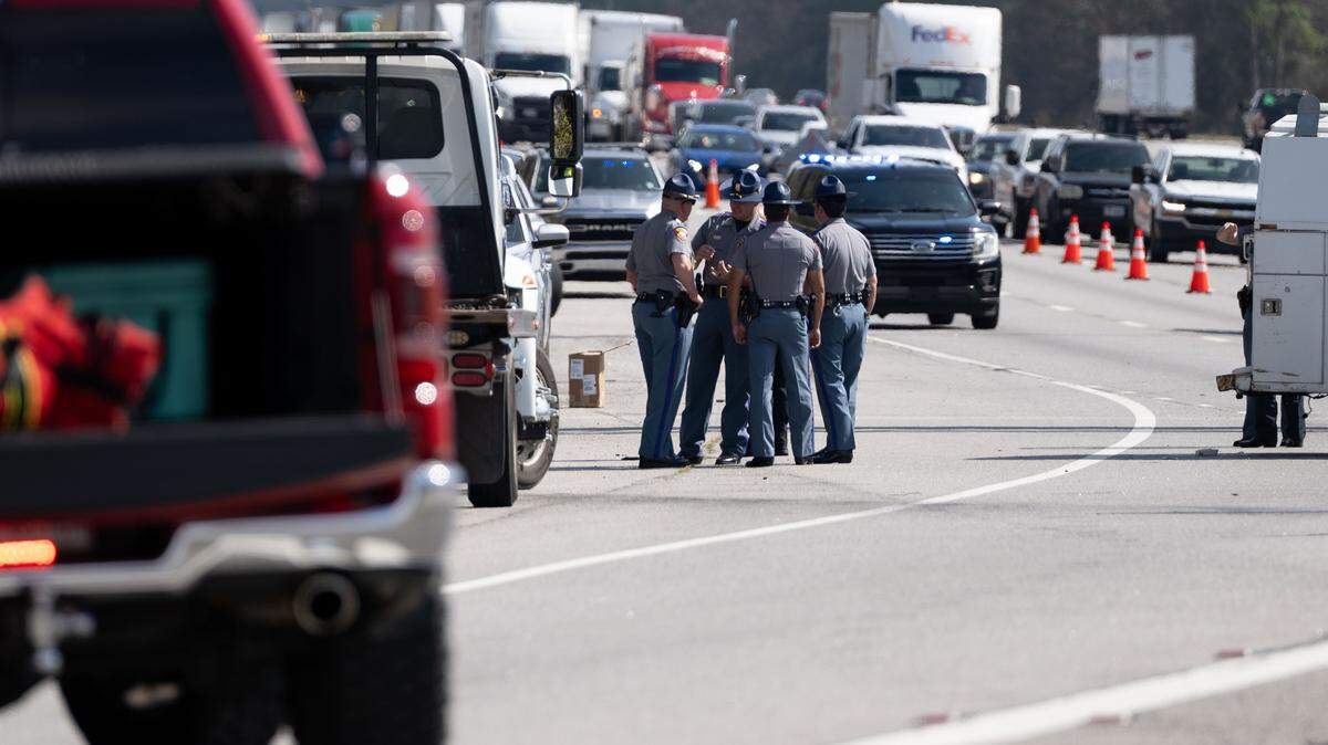 Police officers huddle at Exit 50 on the I-10 as traffic begins to build up behind them on Wednesday, Feb. 18, 2026.