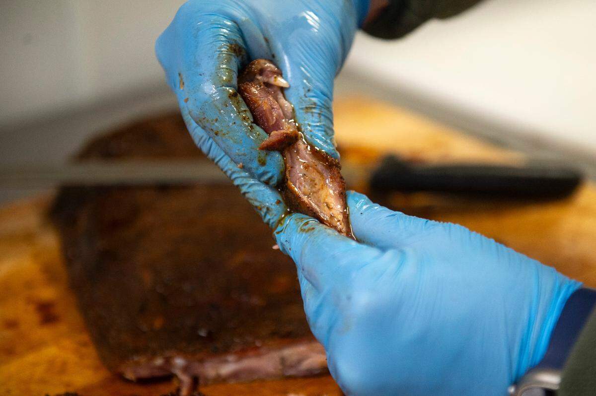 Joseph Mason, owner of 4 Bulls Farm to Table restaurant and the adjacent butcher shop, shows off the juicy pork rib as he works in the kitchen of the restaurant in Ocean Springs on Monday, Jan. 6, 2025.