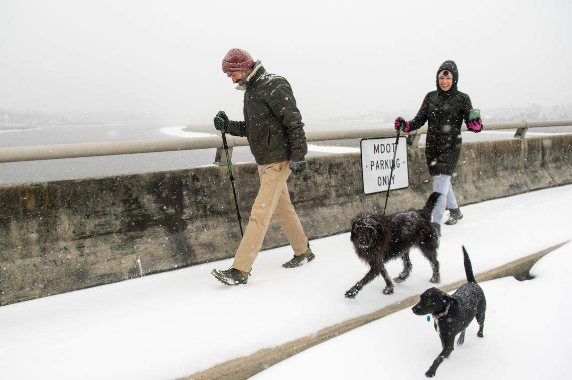 Pedestrians walk through the snow along the Fort Bayou Bridge during a winter storm on the Mississippi Coast on Tuesday, Jan. 21, 2025.
