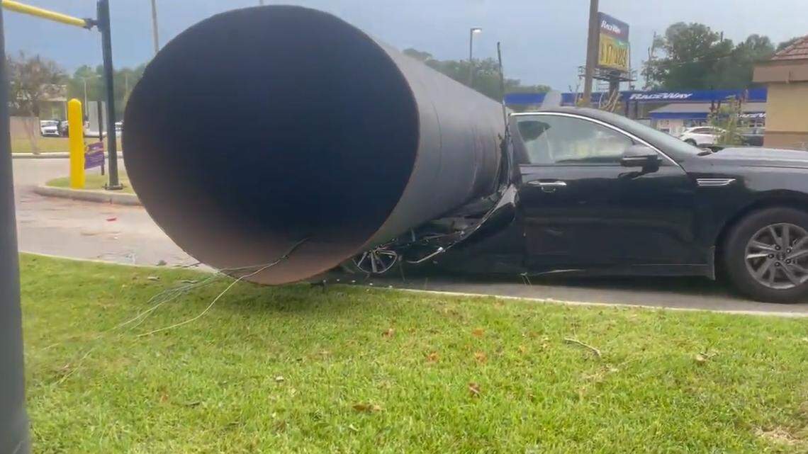 A Louisiana woman became trapped when storm winds blew a Taco Bell sign onto the back of her car in the restaurant drive-thru, police said. 