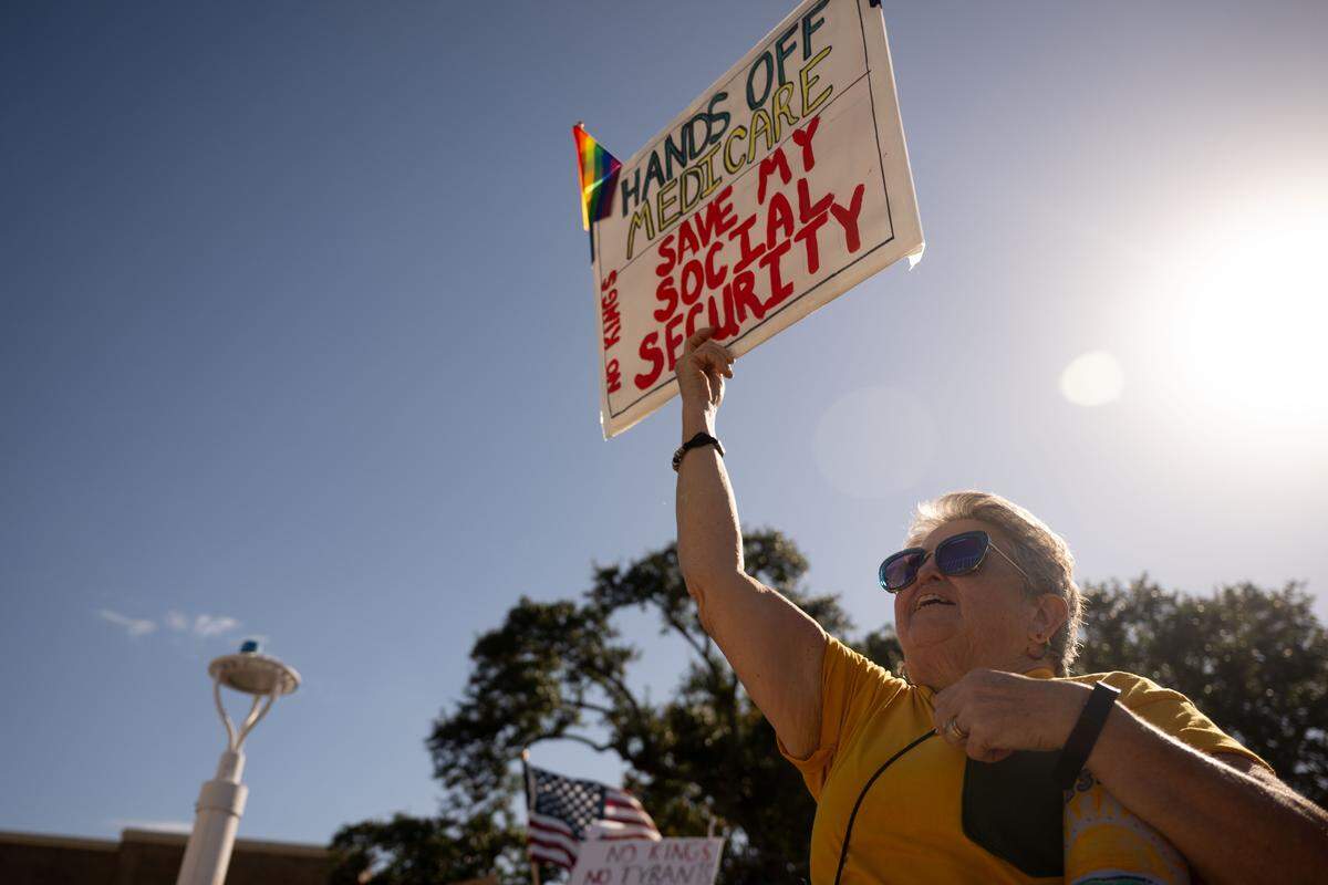 A protester holds up a sign advocating for medicare during a No Kings protest in Gulfport on Saturday, October. 18, 2025.