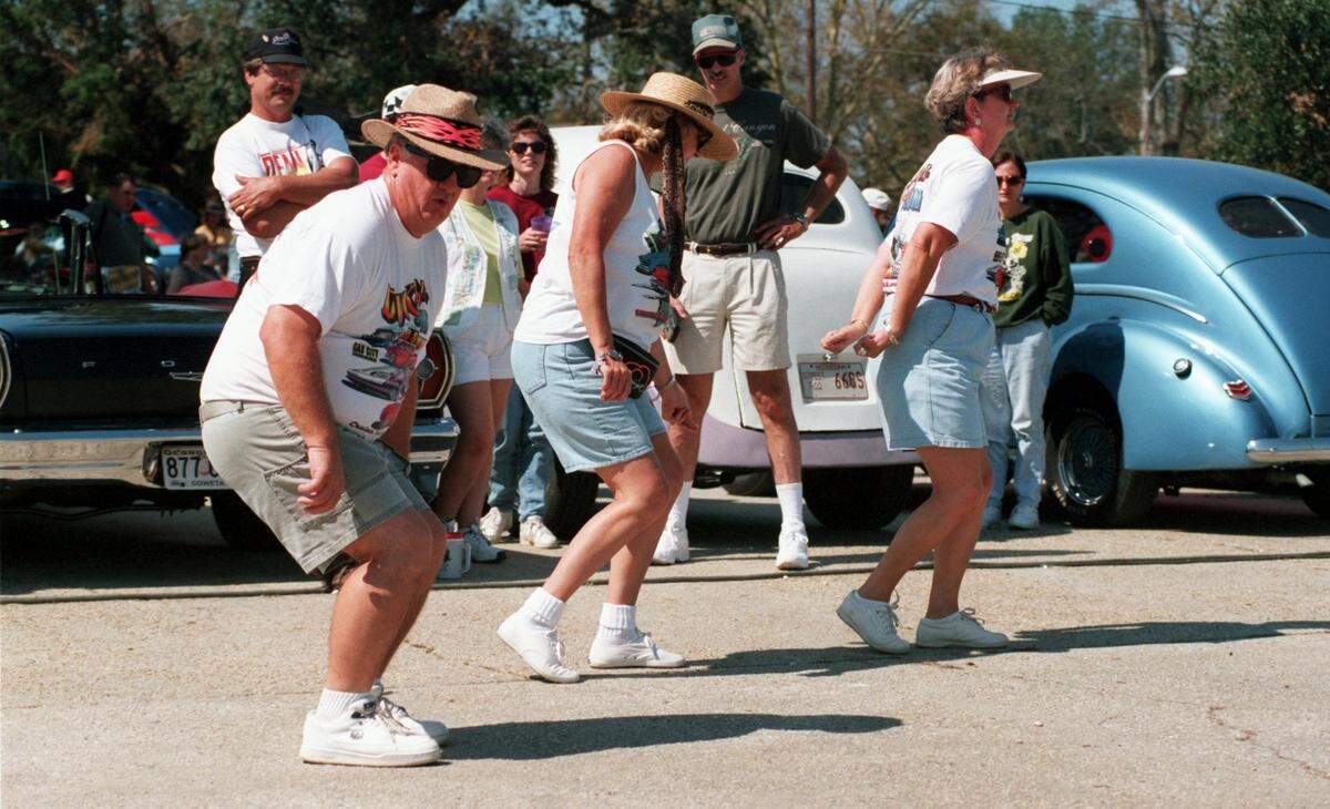 Ken Endicott, left does the electric slide with Jane Petsch and his wife Mary Ann Endicott, all of Newnan, Ga. on October 10, 1998 during Cruisin’ the Coast at Point Cadet. Hundreds came to see vintage cars at Point Cadet during annual event.