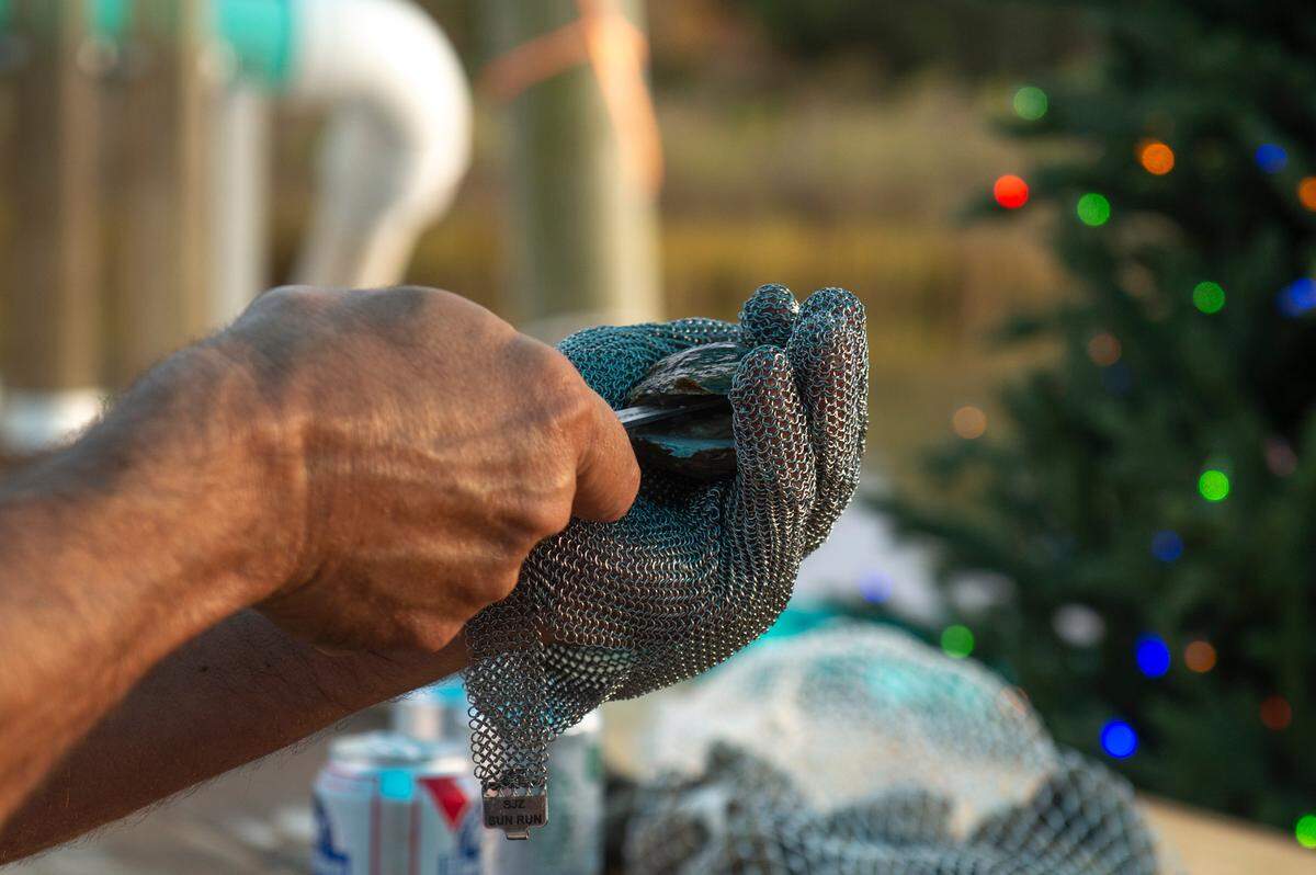 Matthew Mayfield, a co-owner and co-founder of Eagle Point Oyster Co., shucks oysters for a friend at Ocean Springs Harbor on Friday, Dec. 1, 2023.