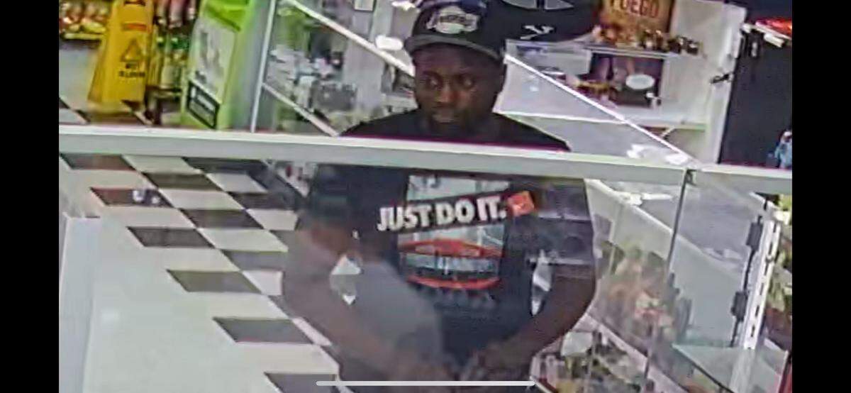 A suspect of the grand larceny is pictured making a purchase before helping to load a stolen car onto a flatbed.