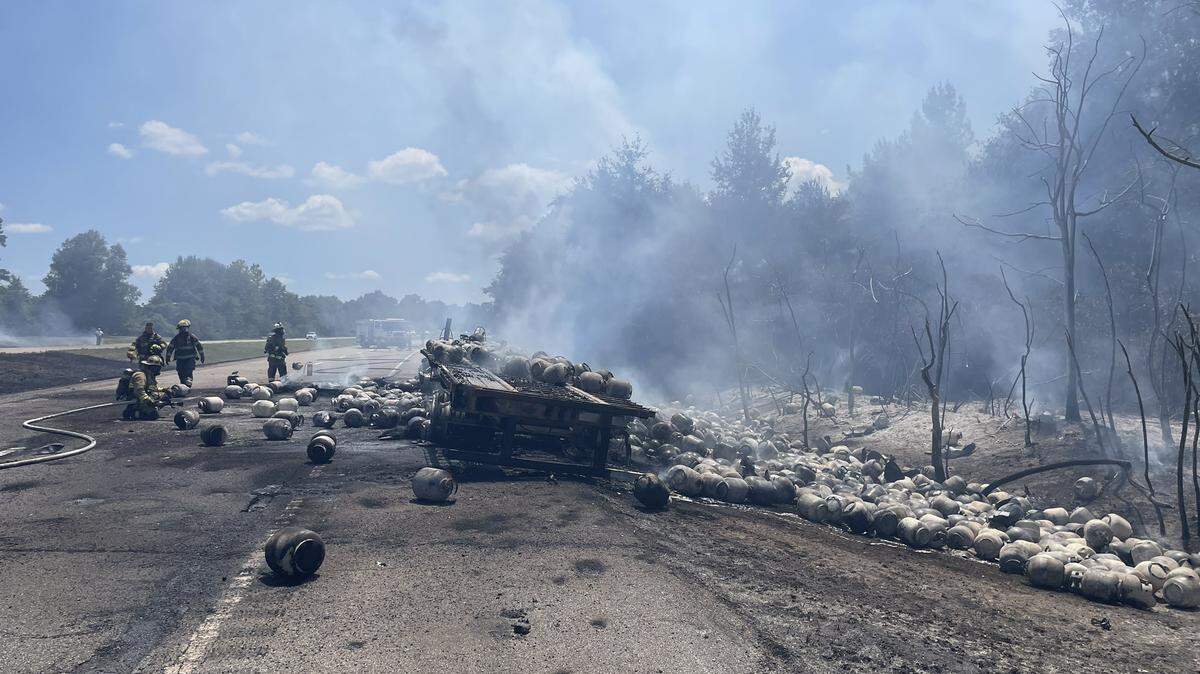 Firefighters work to stop fire spread on Interstate 59 near Poplarville on Monday, Aug. 14, 2023. The interstate was closed after the semi-truck, which was carrying propane tanks, caught fire.