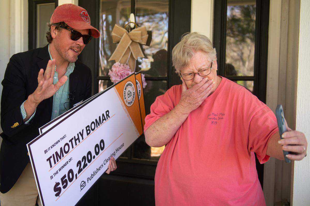 Publishers Clearing House Prize Patrol member Howie Guja and Sandra Bomar FaceTime Timothy Bomar to let him know he won a prize as they stand outside the Bomar’s home in Ocean Springs on Wednesday, March 19, 2025.