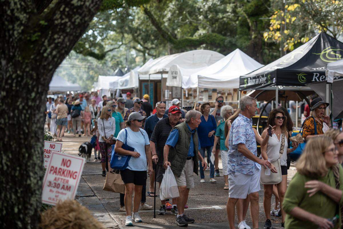 People walk among tents selling art along Washington Avenue during the Peter Anderson Festival in Ocean Springs. Some people will ride Amtrak to Biloxi that weekend and take a bus or Uber across the bay to the festival. 