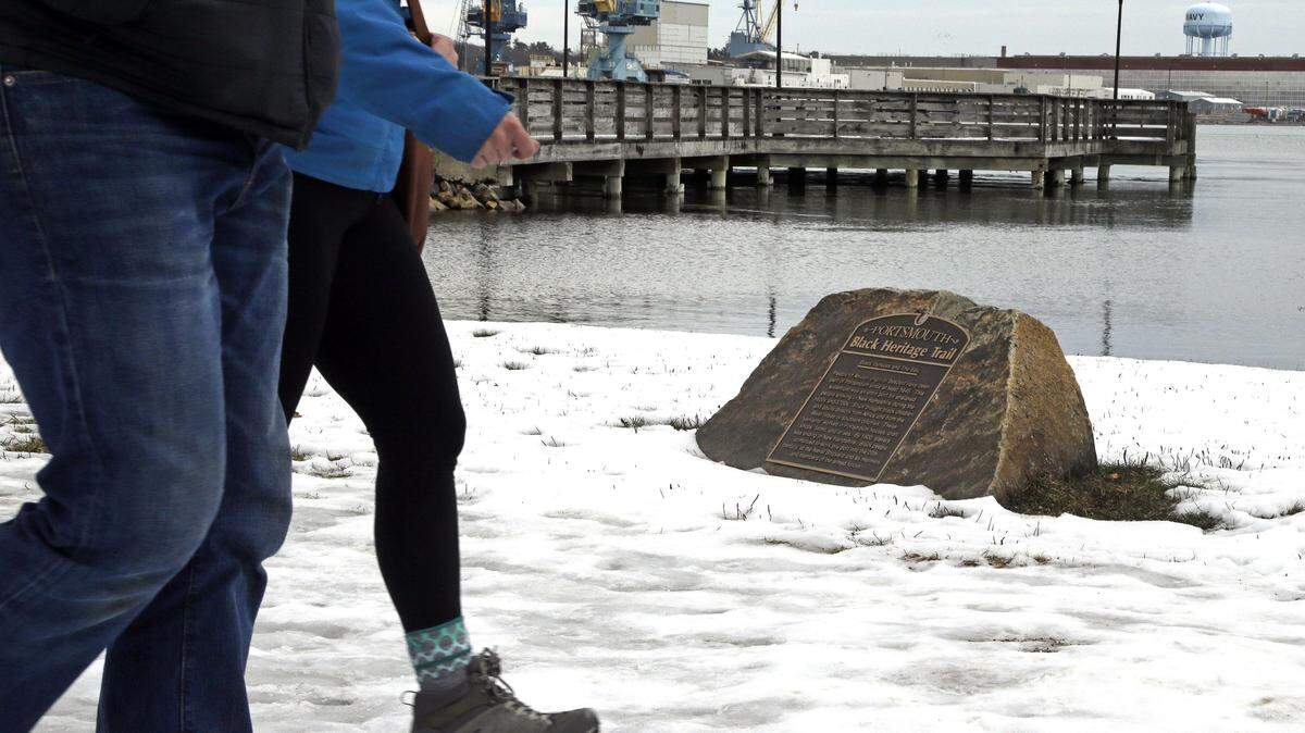 In this Tuesday, Jan. 26, 2016 photo, pedestrians walk by a slavery port marker in Portsmouth, N.H., identifying a port where slaves arrived or where ships were sent to be used in the trade. A project aimed at bringing the little-known history of some of Americaís most prolific slave-trade ports to the public is moving to its next target: Rhode Island, where some 1,000 slave-trading voyages were launched. (AP Photo/Elise Amendola)