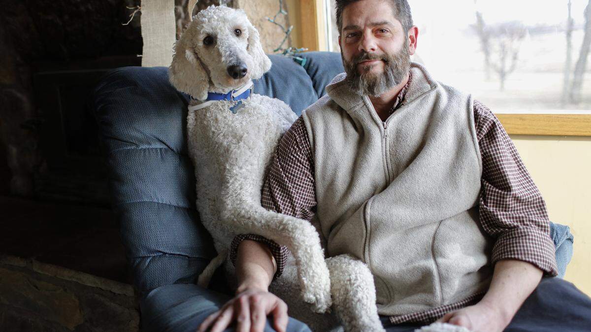 BRIAN PETERSON/MINNEAPOLIS STAR TRIBUNE/TNSChris Cline has been Photoshopping his golden doodle Juji - in a gargantuan proportion - into photos that have made his Instagram account a phenomenon and enable him to earn a living doing this for other people and their pets. Here, Cline and Juji sit in Juji's favorite chair in Buffalo, Minn.