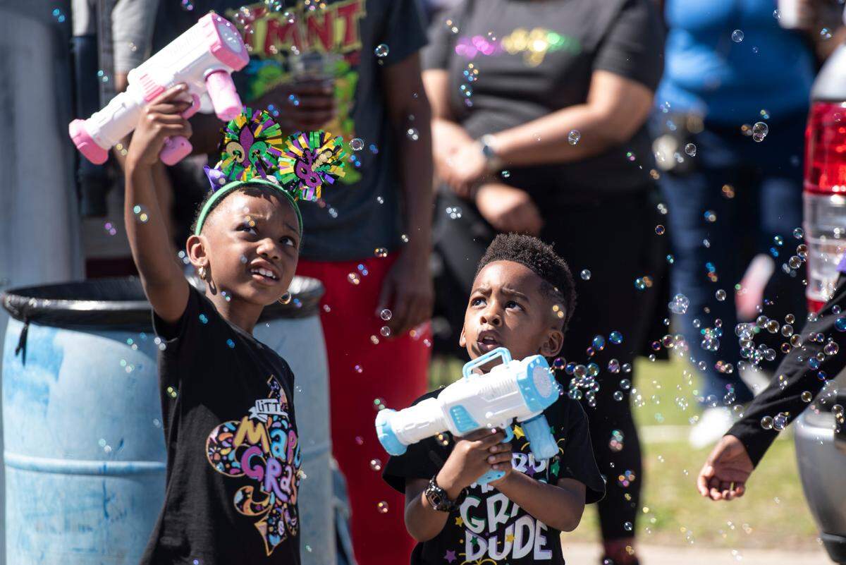 Parade attendees play with bubble guns during the Jackson County Carnival Association Mardi Gras parade in Pascagoula on Saturday, March 1, 2025.